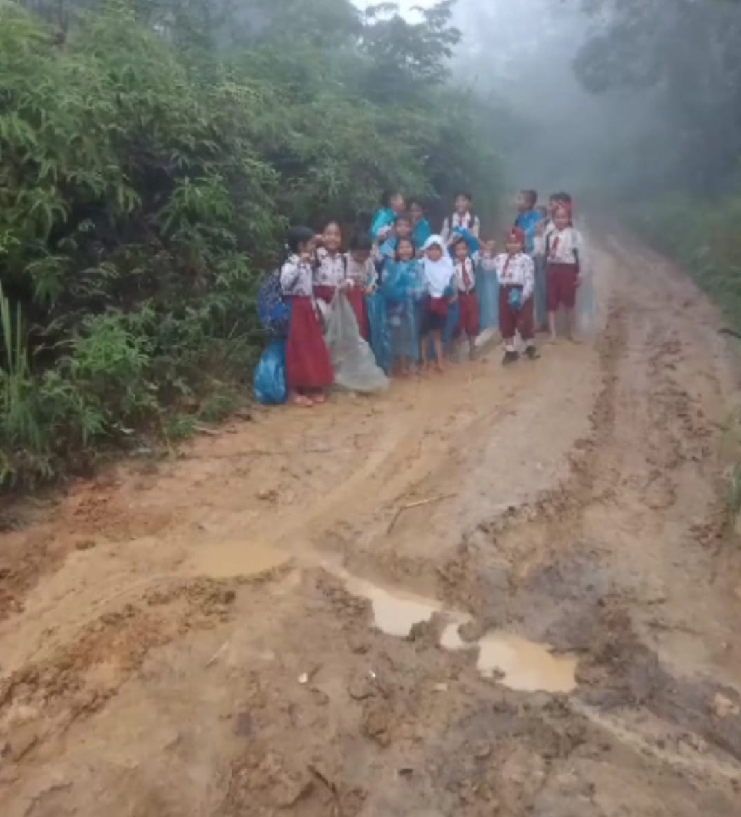 
Anak-anak sekolah SD saat melalui jalan yang becek dan berlumpur di Siunggam Dolok Paluta.
